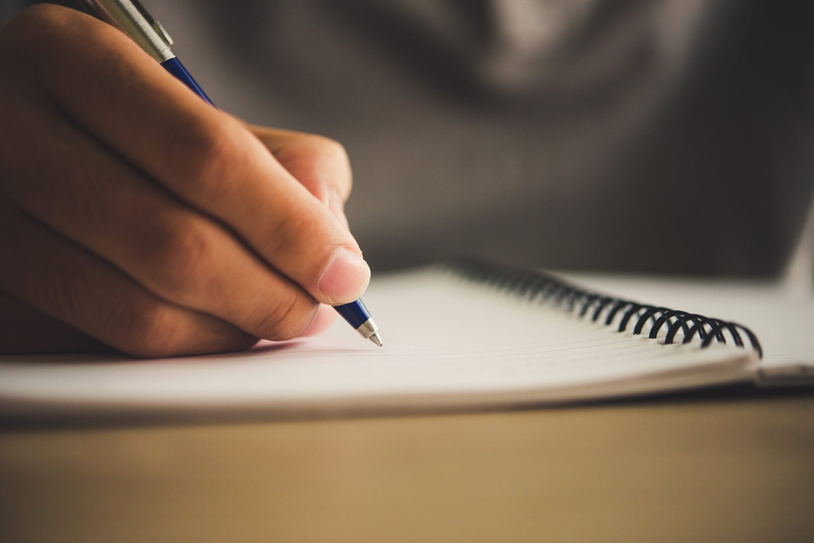 Manos escribiendo una carta en un cuaderno